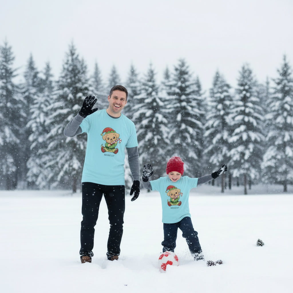 Man and child in matching light blue shirts with a teddy bear graphic in a snowy landscape.